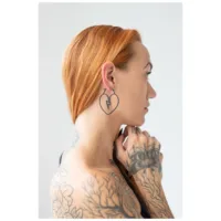 Nainen kuparin värisillä hiuksilla käyttää mustia sydänkorvakoruja