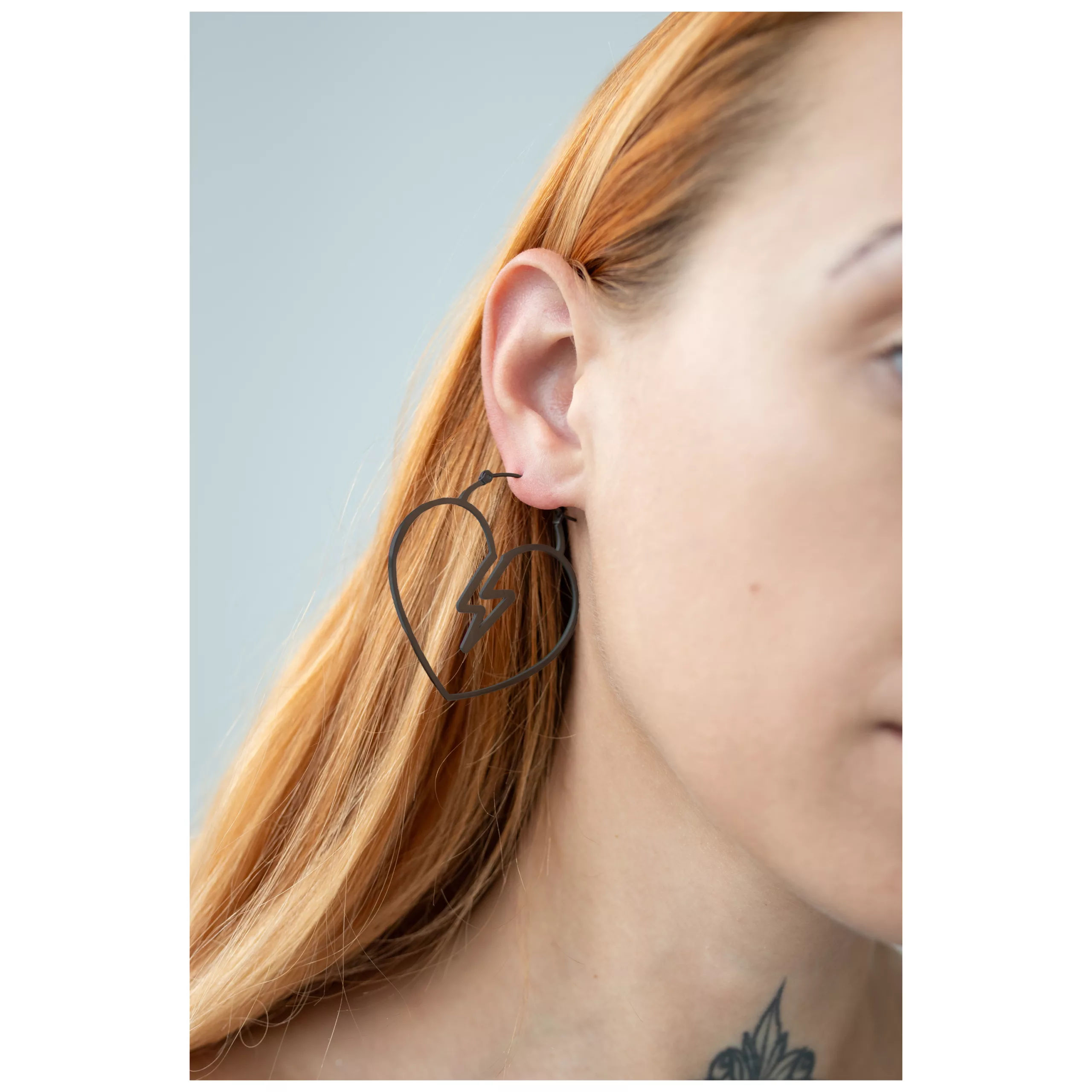 Mustat sydämenmuotoiset korvakorut korvassa, jossa on vaaleat hiukset