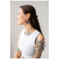 Daisy Hoops mustana kirurginteräksestä Mustat Daisy Hoops -korvakorut kirurginteräksestä tatuoidulla naisella neutraalissa taustassa