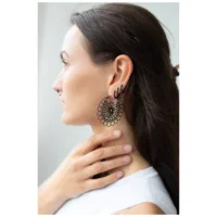 Musta Daisy Hoops -korvakorut kirurginteräksestä Musta Daisy Hoops -korvakorut kirurginteräksestä ruskeahiuksisella naisella, jolla on valkoinen paita