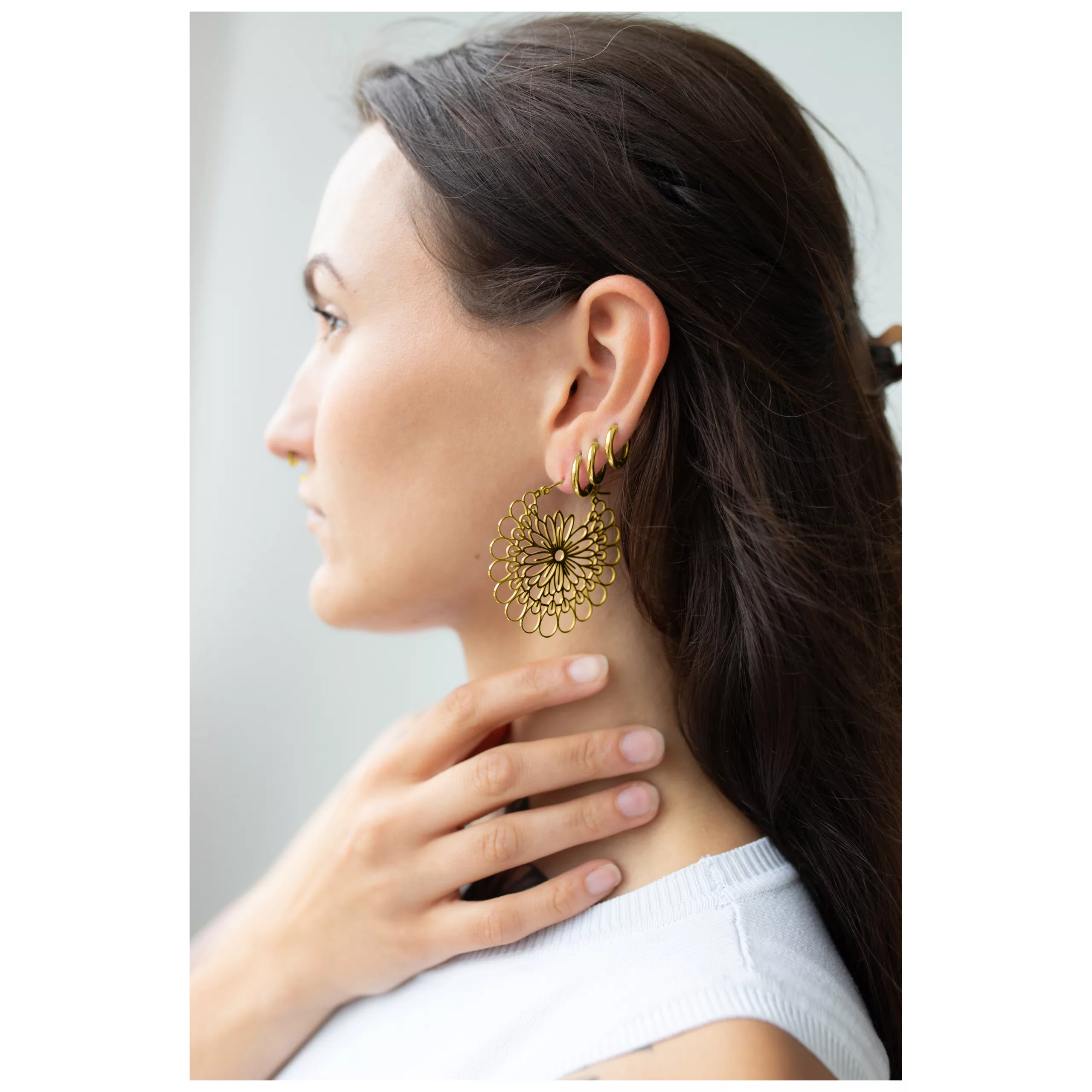 Kultaiset Daisy Hoops -korvakorut korvassa Kultaiset Daisy Hoops -korvakorut naisen korvassa