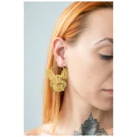 Nainen käyttää kultaisia Bulldog Hoops -korvakoruja vaaleaa taustaa vasten