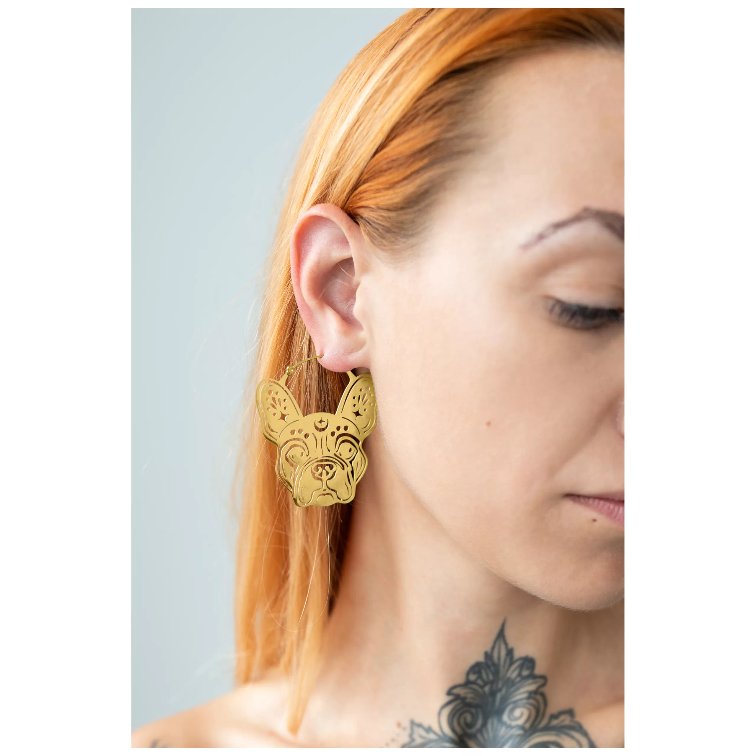 Nainen käyttää kultaisia Bulldog Hoops -korvakoruja vaaleaa taustaa vasten