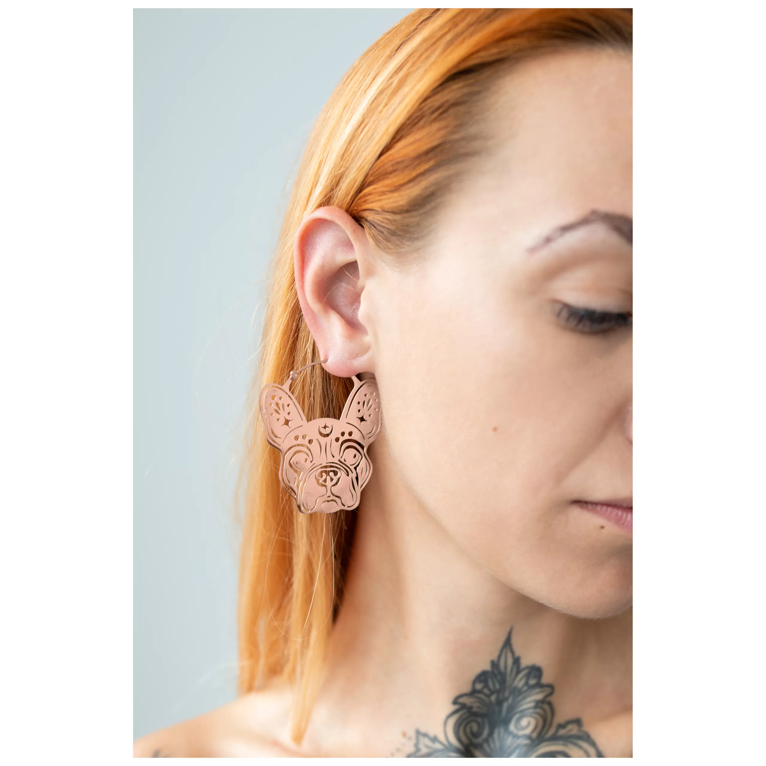 Nainen ruusukultaisilla Bulldog-korvakoruilla vaalealla taustalla