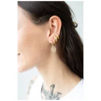 Kultaiset Little Eye Hoops naisen korvassa, kiiltävät ja elegantit