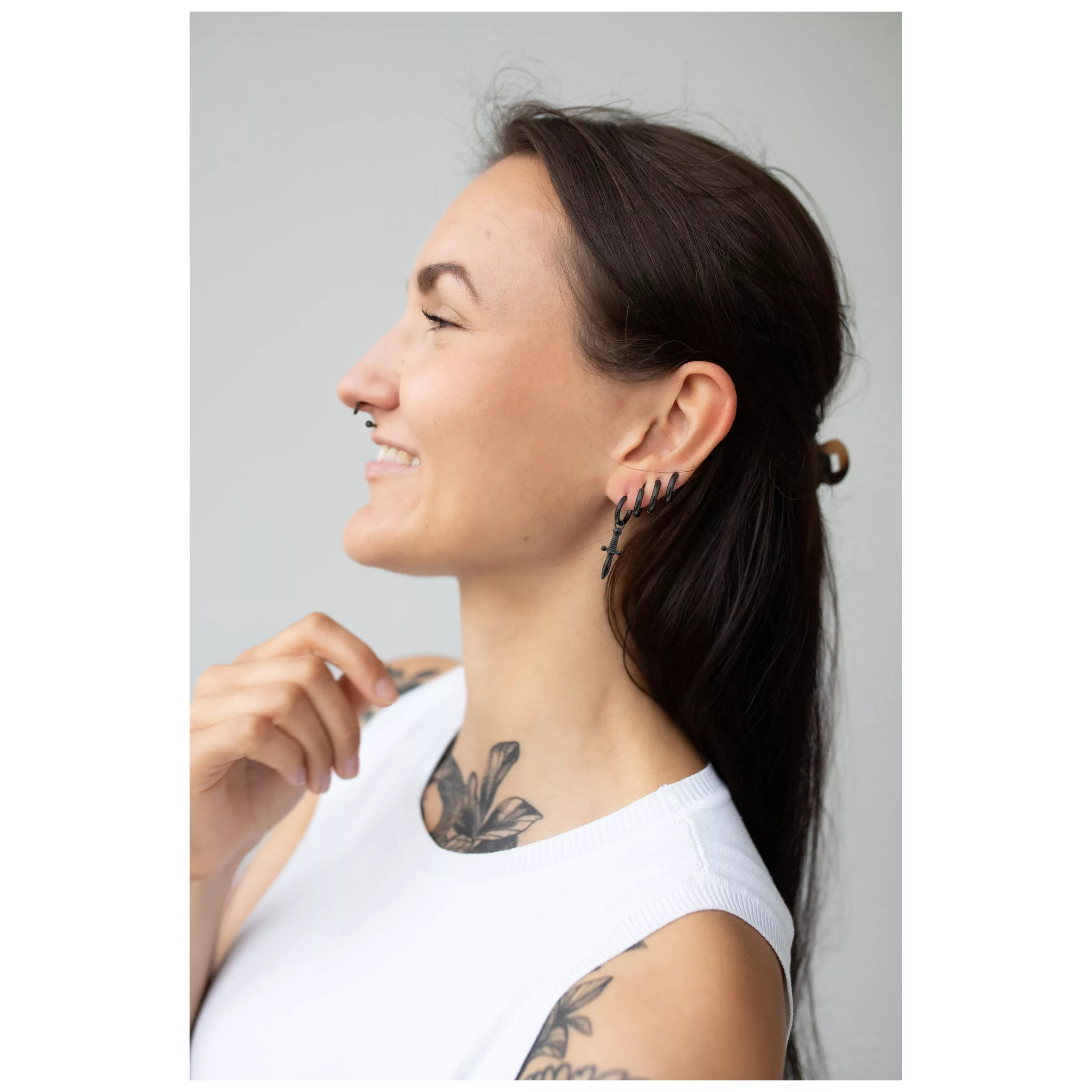 Pitkähiuksinen nainen käyttää pieniä mustia miekka-korvakoruja