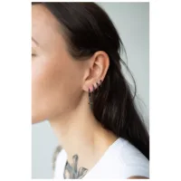 Nainen, jolla on mustat Little Sword -korvakorut valkoisella taustalla