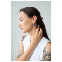 Nainen mustilla Little Thunderstorm Hoops -korvakoruilla vaaleaa taustaa vasten