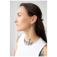 Musta korvakorut naisen korvassa, sivukuva, valkoinen tausta