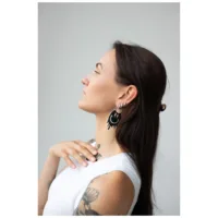 Pitkät tummat hiukset omaava nainen käyttää hopeisia Smiley Big Hoops -korvakoruja