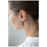 Mustat kolmio-korvarenkaat modernissa tyylissä Nainen mustilla kolmio-korvarenkailla kirurginteräksestä, sivuprofiili