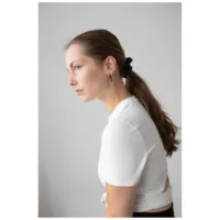 Musta Little Long Spike Hoops korvassa Nainen mustilla Little Long Spike Hoops korvakoruilla harmaata taustaa vasten