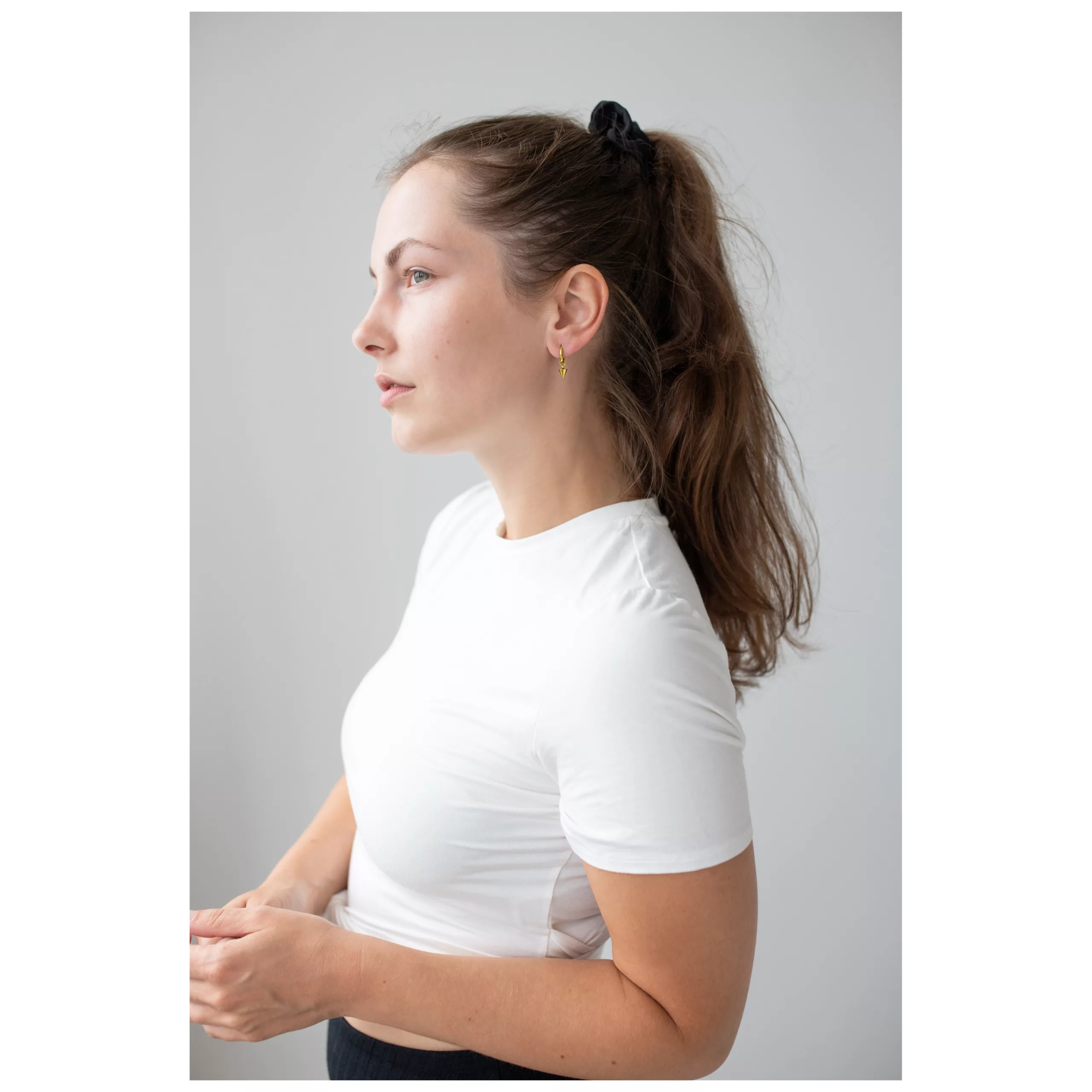 Kultaiset Little Short Spike Hoops korvassa Nainen valkoisessa T-paidassa ja kultaiset Little Short Spike Hoops neutraalilla taustalla