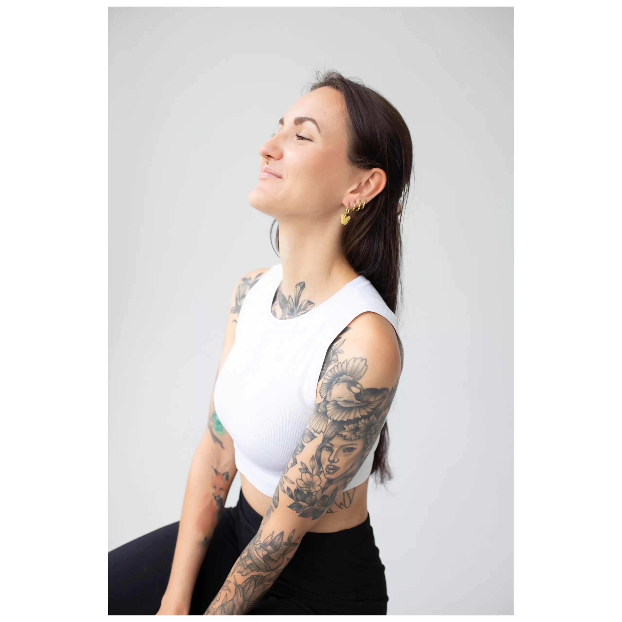 Nainen kultaisilla Little Bulldog -korvakoruilla neutraalia taustaa vasten