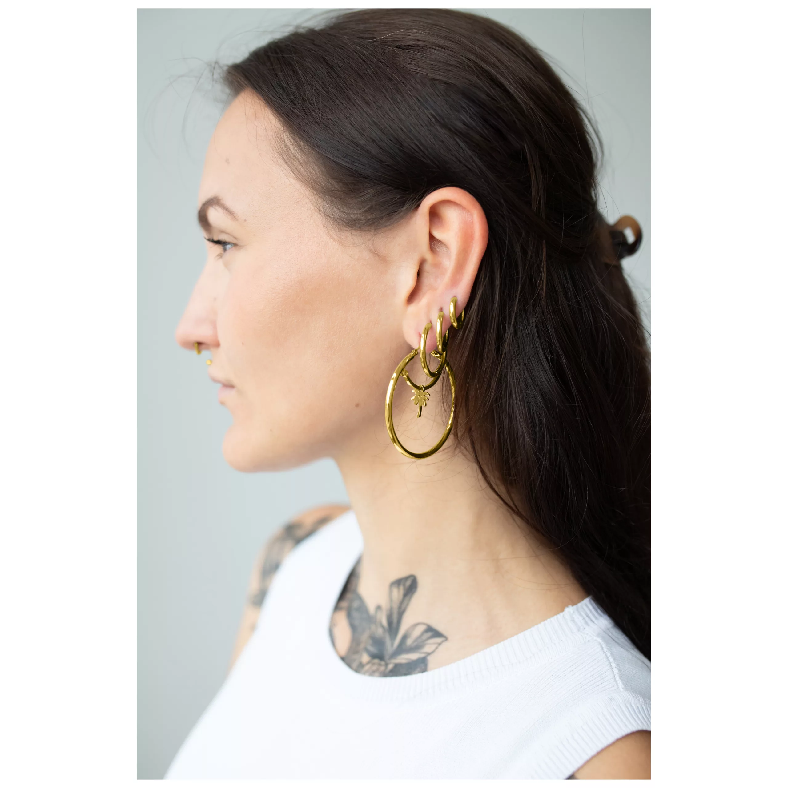 Kultaiset korvarenkaat klipsilukolla 45 MM Nainen kultaisilla 45 MM korvarenkailla, sivukuva, neutraali tausta