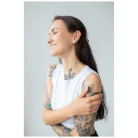 Tatuoitu nainen käyttää mustia Little Moonchild Hoops -korvakoruja