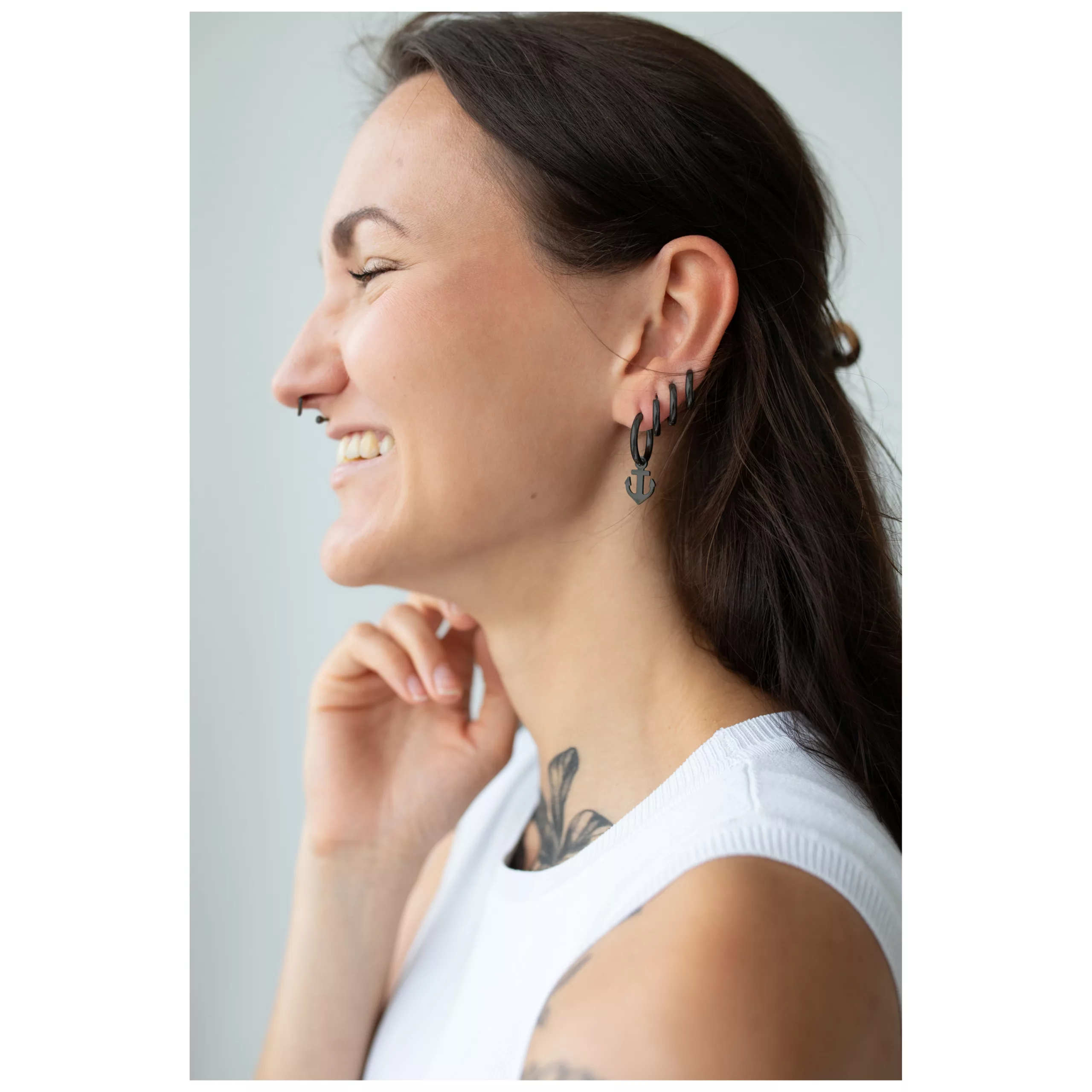 Nainen mustilla Little Anchor Hoops korvakoruilla, valkoinen toppi