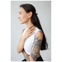 Pitkähiuksinen nainen käyttää kultaisia Little Anchor Hoops -korvakoruja, sivuprofiili