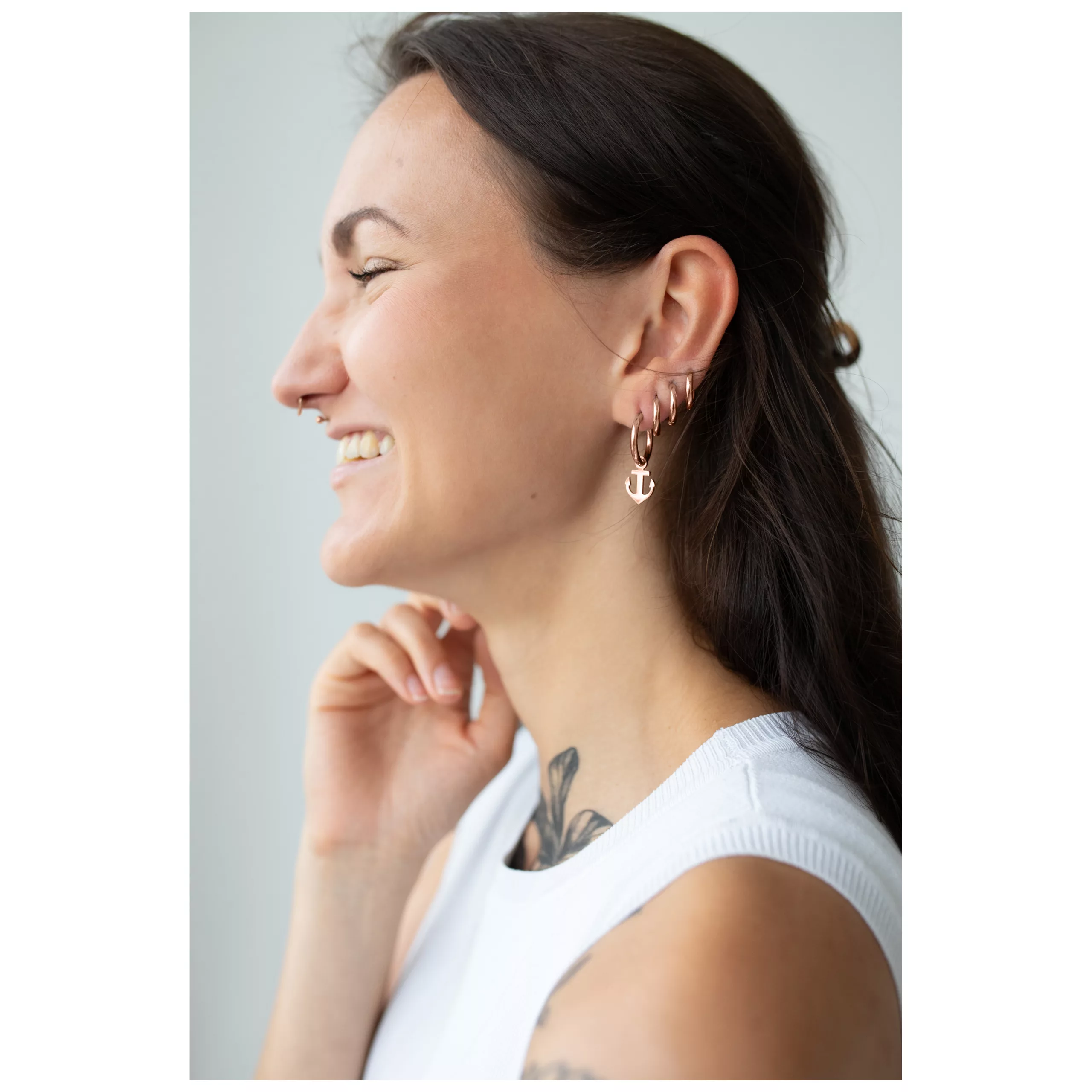 Nainen ruusuhopeisilla ankkurikoruilla, hymyilevä, sivuprofiili