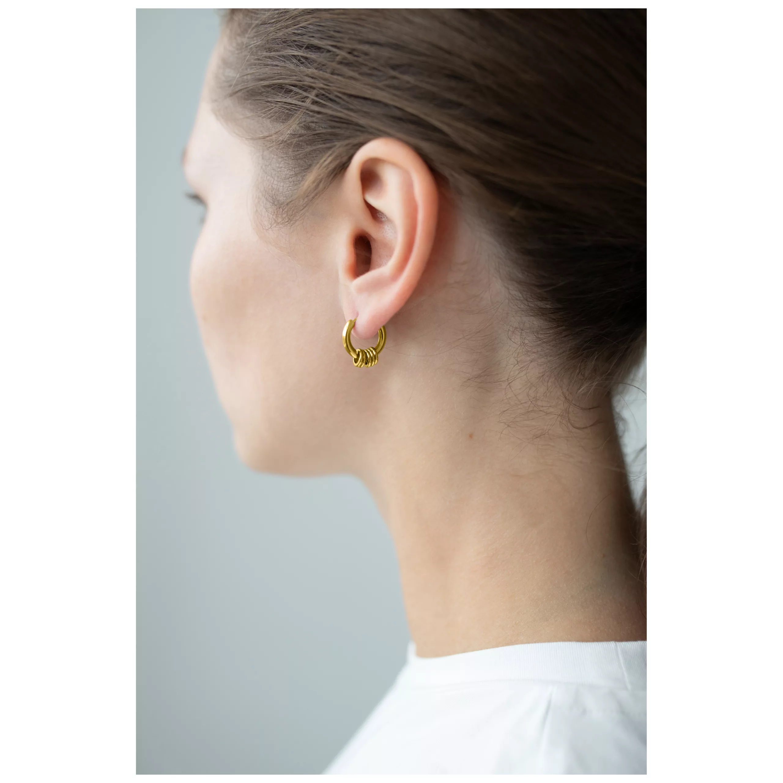 Kultaiset Little 5 Rings Hoops korvassa Kultaiset Little 5 Rings Hoops korvakorut korvassa vaalealla taustalla