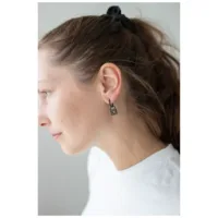 Musta Little Lock Hoops korvissa Nainen käyttää mustia Little Lock Hoops -korvakoruja valkoisella taustalla