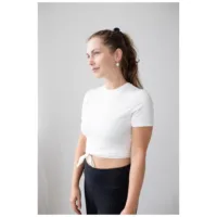 Nainen käyttää ruusuhopeisia korvakoruja hymyillä vaalealla taustalla