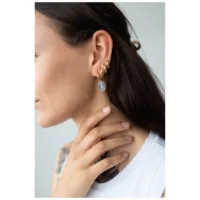 Nainen käyttää kultaisia Little Mystic Snake Hoops -korvakoruja klipsikiinnityksellä