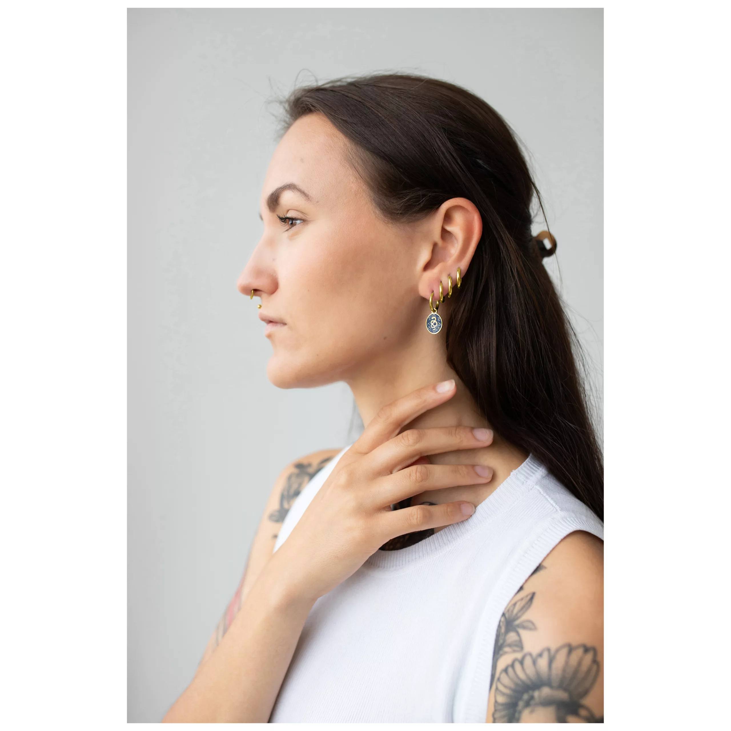 Nainen kultaisilla Little Mystic Snake -korvarenkailla harmaata taustaa vasten