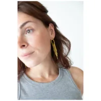 Kultaiset Snakechain Hoops -korvakorut korvassa Nainen käyttää kultaisia Snakechain Hoops -korvakoruja klipsikiinnityksellä, hiukset auki