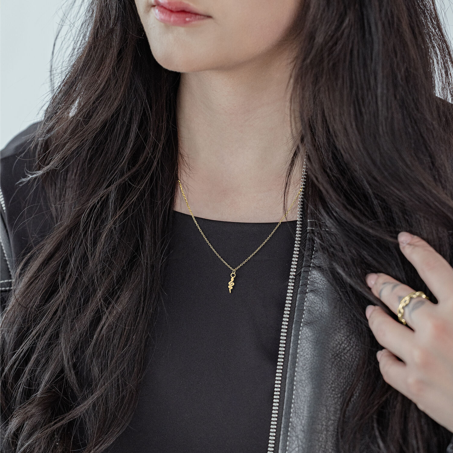 Frau mit goldener Little Snake Kette, schwarzes Outfit, lange Haare