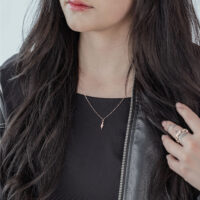 Frau mit roségoldener Little Snake Kette aus Chirurgenstahl, schwarzes Outfit