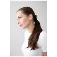 Kultaiset Set Crystals korvakorut korvassa Nainen ruskeilla hiuksilla käyttää kultaisia korvakoruja vaalealla taustalla