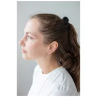 Nainen kultaisilla sydänkorvakoruilla ja valkoisella yläosalla profiilissa