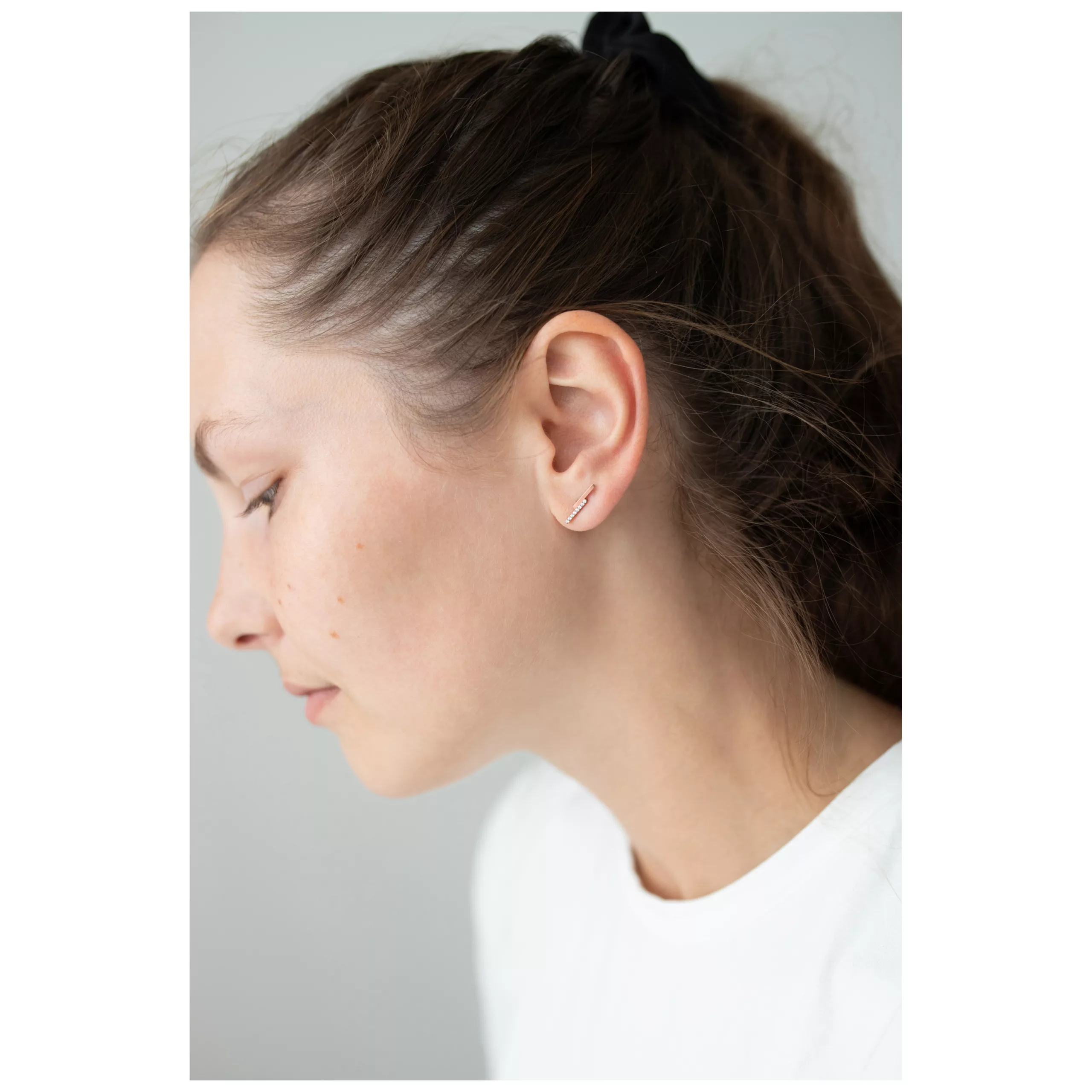 Nainen Rosekultaiset korvakorut Double Beam Crystal harmaata taustaa vasten