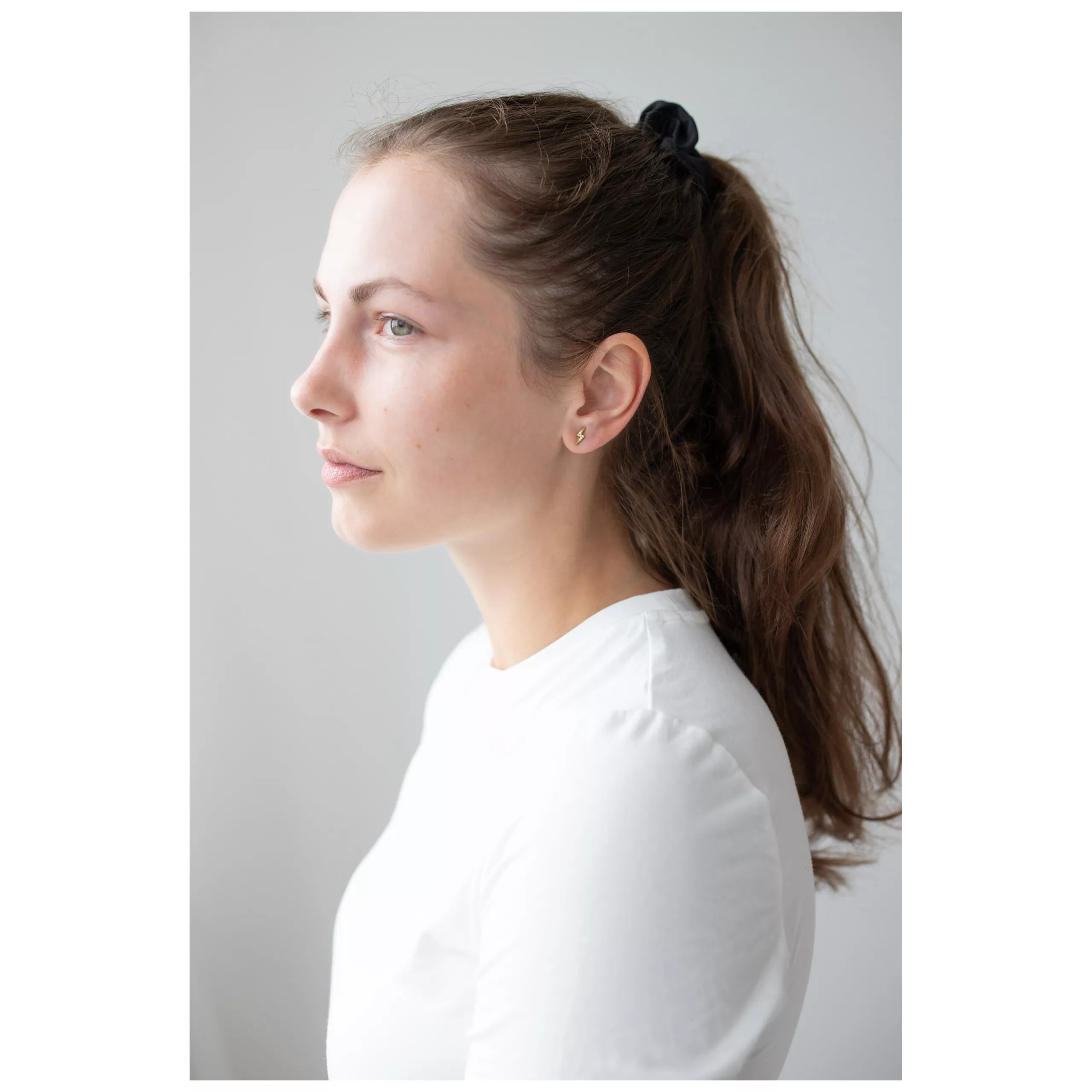 Kultaiset Crystal Lightning -korvakorut Nainen kultaisilla Crystal Lightning -korvakoruilla, sivulta