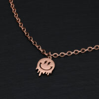 Roségoldenes Armband mit Smiley-Anhänger auf schwarzem Hintergrund