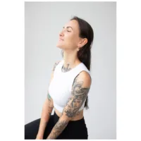 Nainen valkoisessa topissa käyttää rosékultaisia Little Bulldog Hoops -korvakoruja vaalealla taustalla