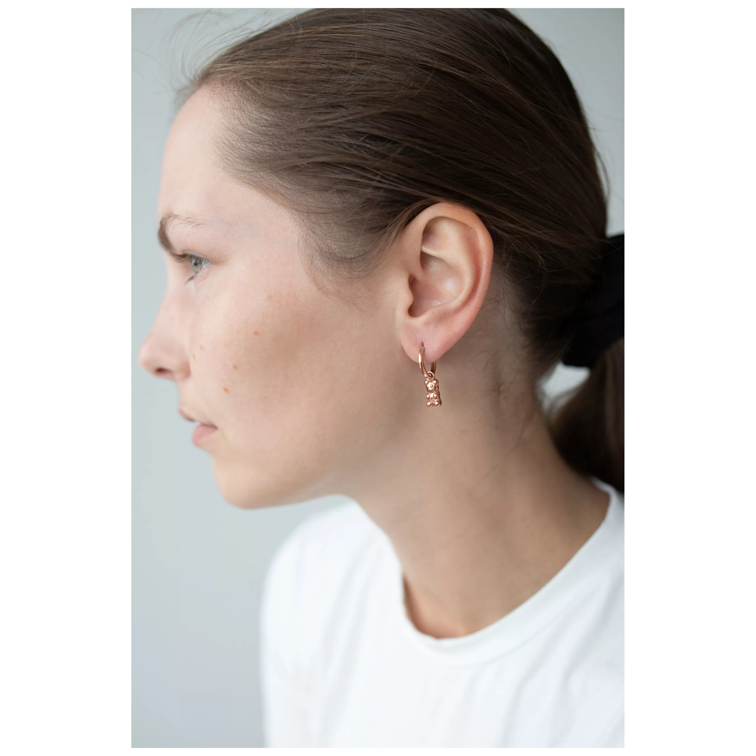 Nainen ruusukultaisilla Gummi Bear korvakoruilla, sivukuva