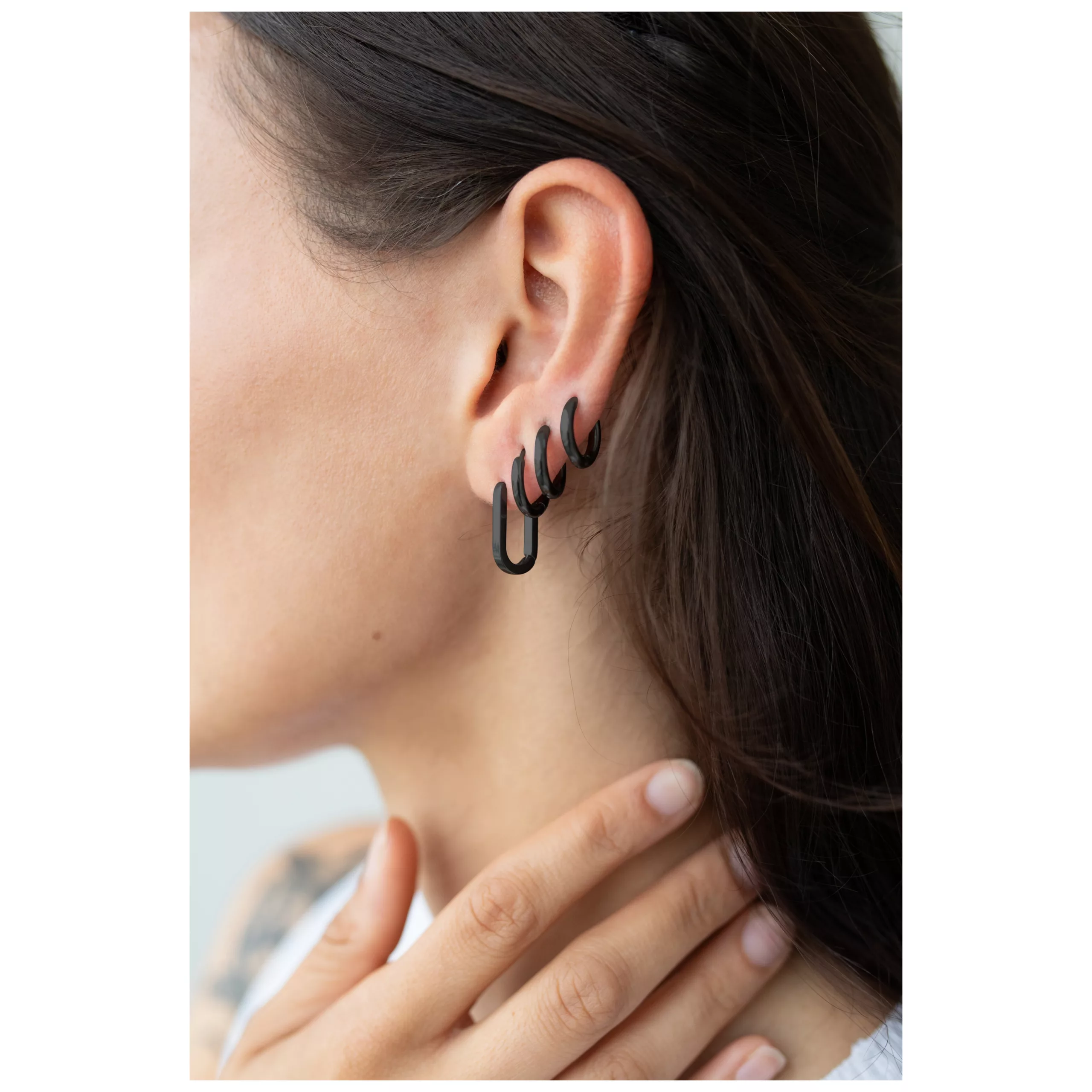 Nainen käyttää mustia ovaali perusrenkaat korvakoruja klipsilukolla