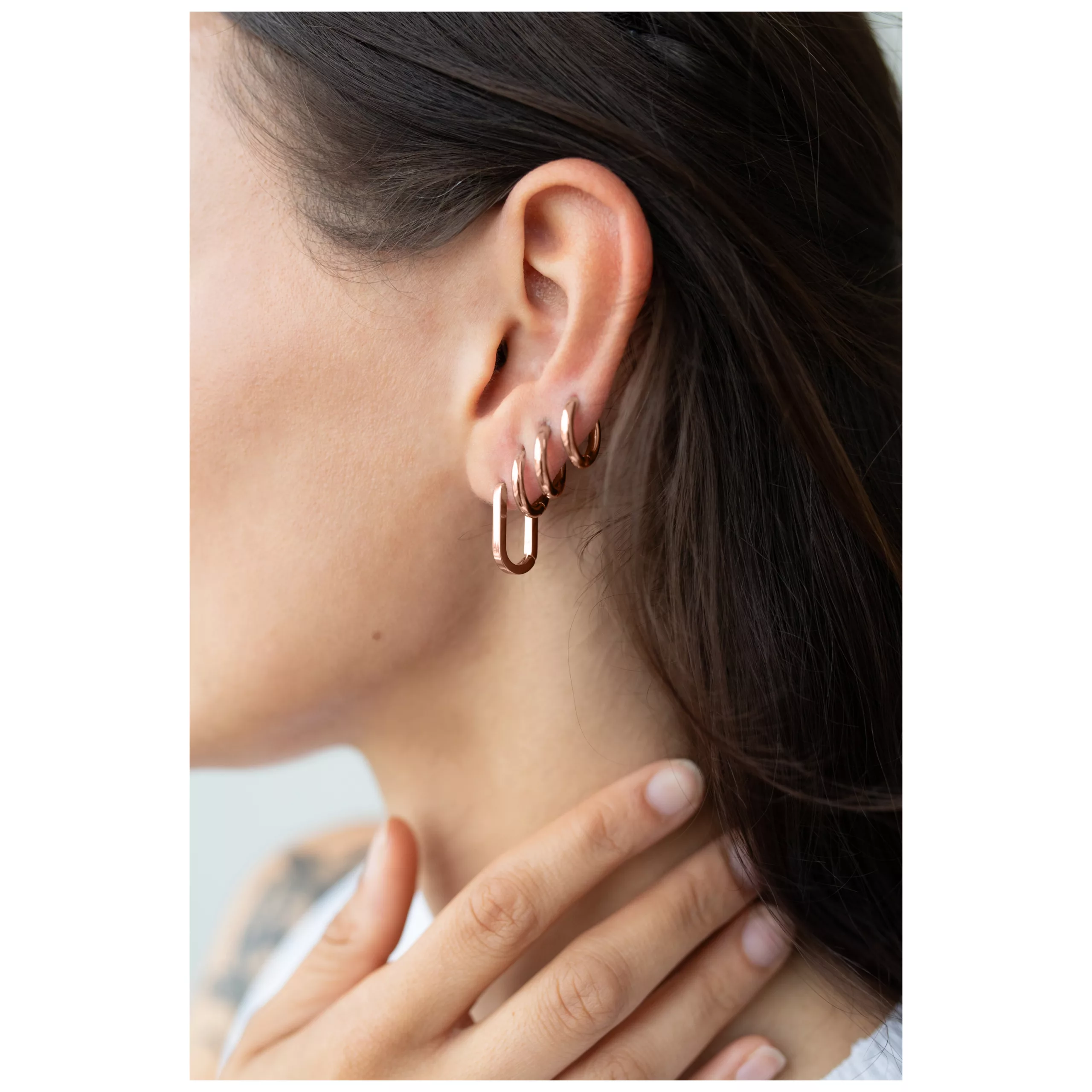 Ruusuhopeat ovaalit perusrenkaat naisen korvassa, lähikuva