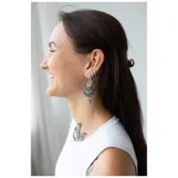 Silberne Barock Ohrringe am Ohr getragen Frau mit lächelndem Gesicht trägt silberne Barock Ohrringe, seitliche Ansicht