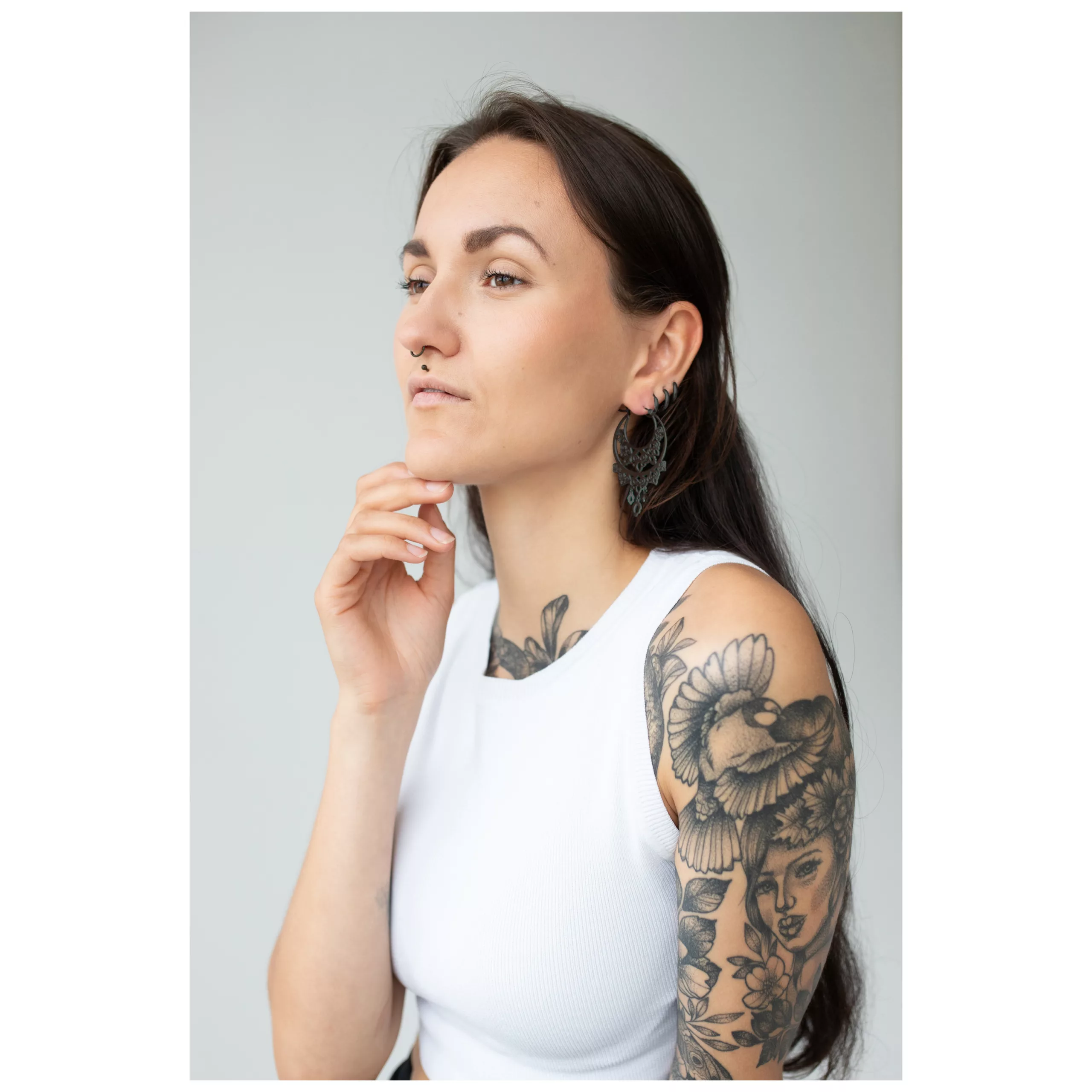 Schwarze Barock Chandelier Hoops im Ohr Frau mit tätowiertem Arm trägt schwarze Barock Chandelier Hoops