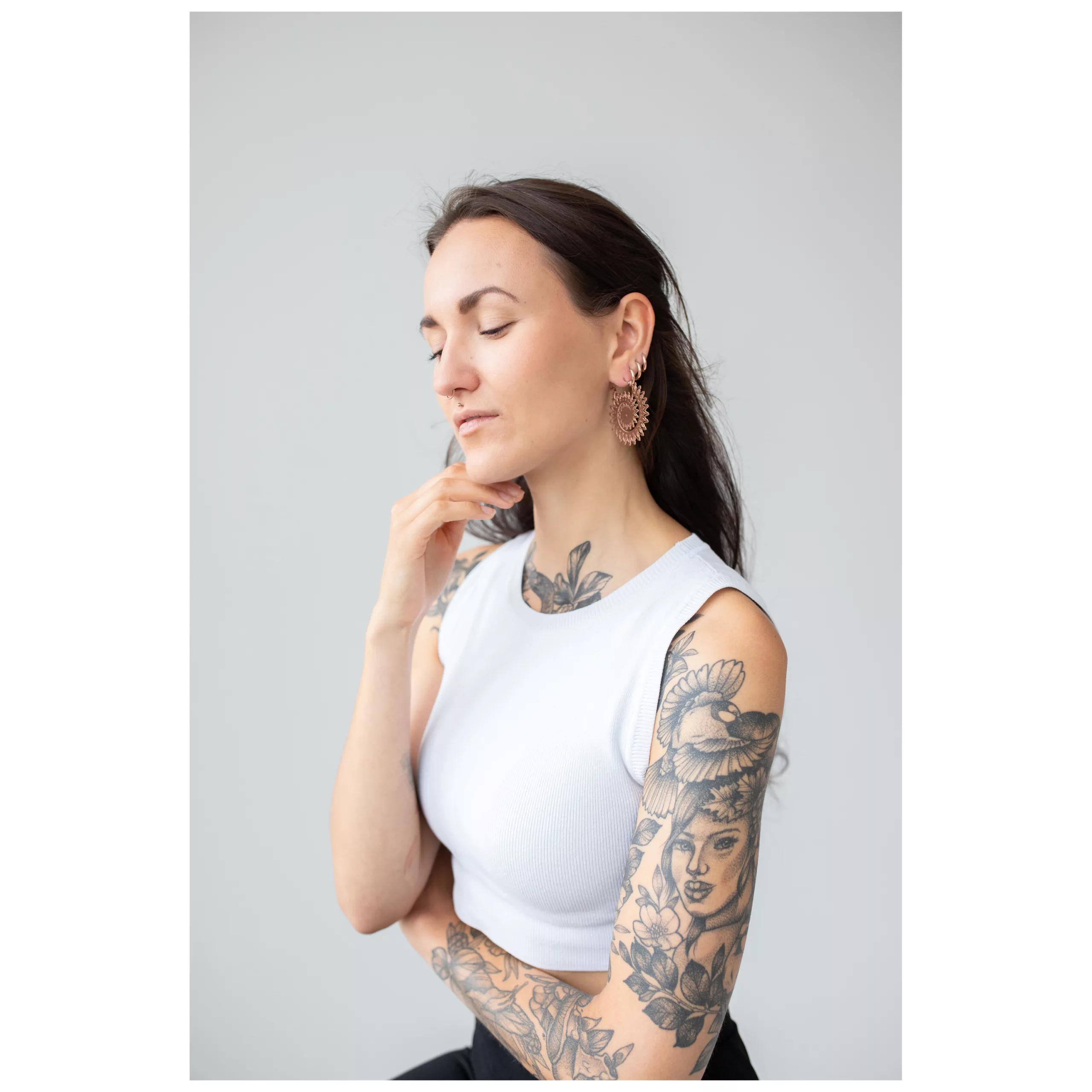 Frau mit roségoldenen Floral Nautilus Creolen vor grauem Hintergrund