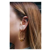 Goldene Ohrringe in Ankerform am Ohr einer Frau mit langem Haar