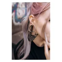 Frau mit Sphynx Hoops in Schwarz, getragen im Ohr, vor urbanem Hintergrund