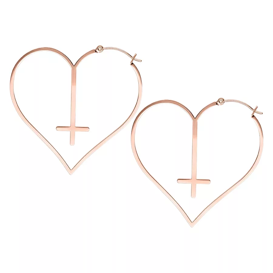 Kaksi rosékultaista sydämenmuotoista korvakorua ristikuviolla valkoisella taustalla