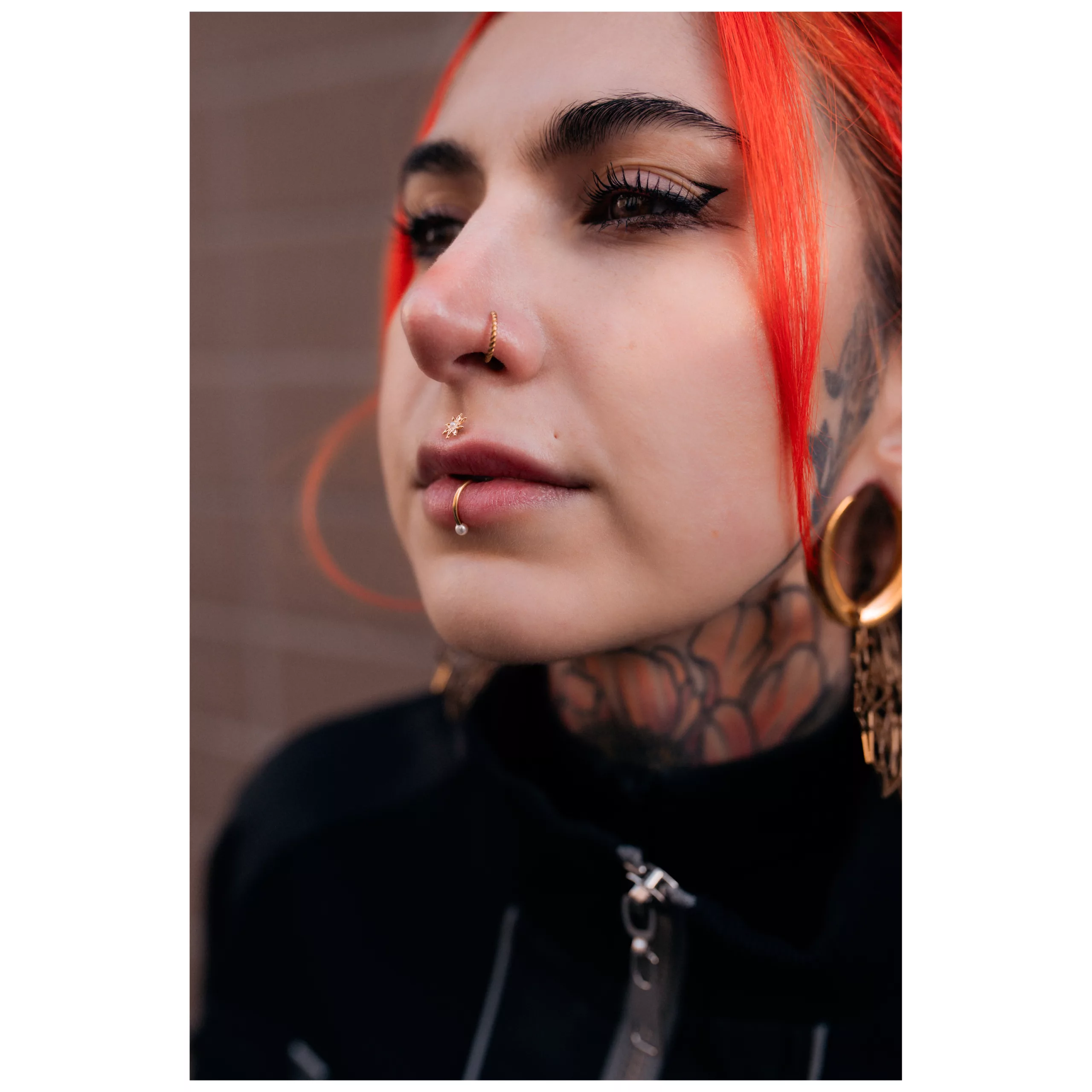 Frau mit rotem Haar trägt goldenen Glossy Pearl Lipcuff und andere Piercings