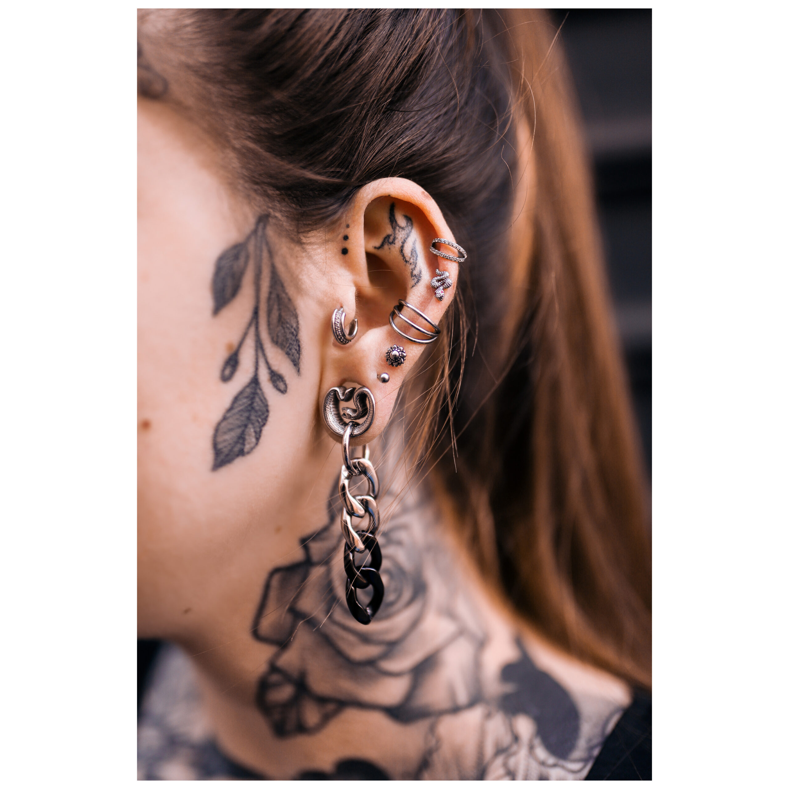 Hopeiset ja mustat Hoops-korvakorut korvassa, jossa on tatuointeja, sivukuva.