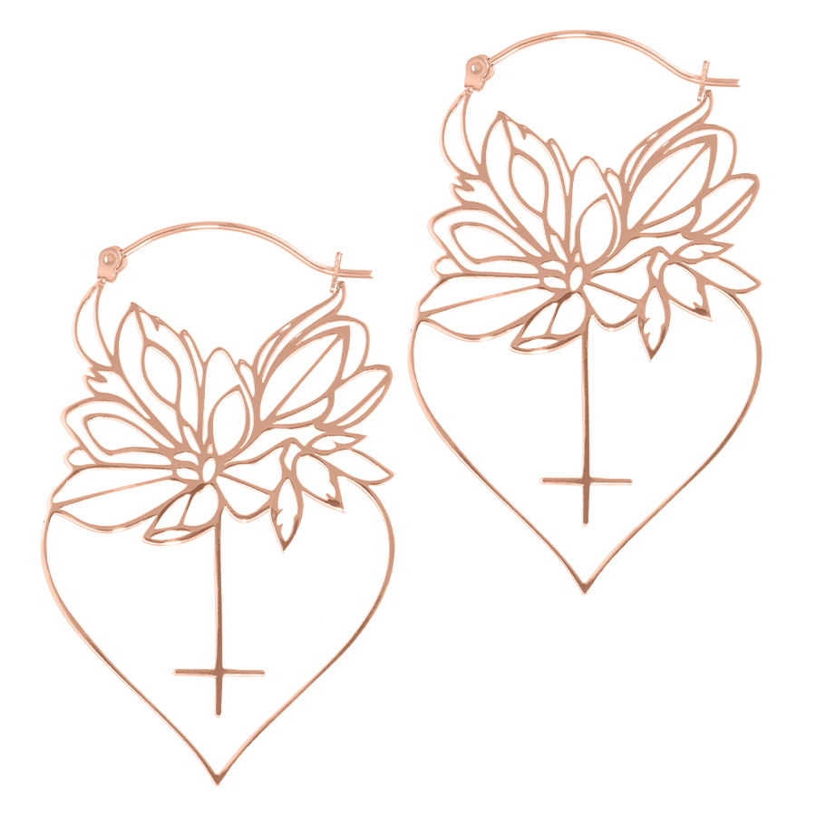 Kaksi ruusukultaista sydämenmuotoista korvakorua, joissa on daaliakukkakuvio, valkoisella taustalla