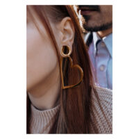 Ruusukultaiset sydänkorvakorut naisen korvassa, taustalla mies